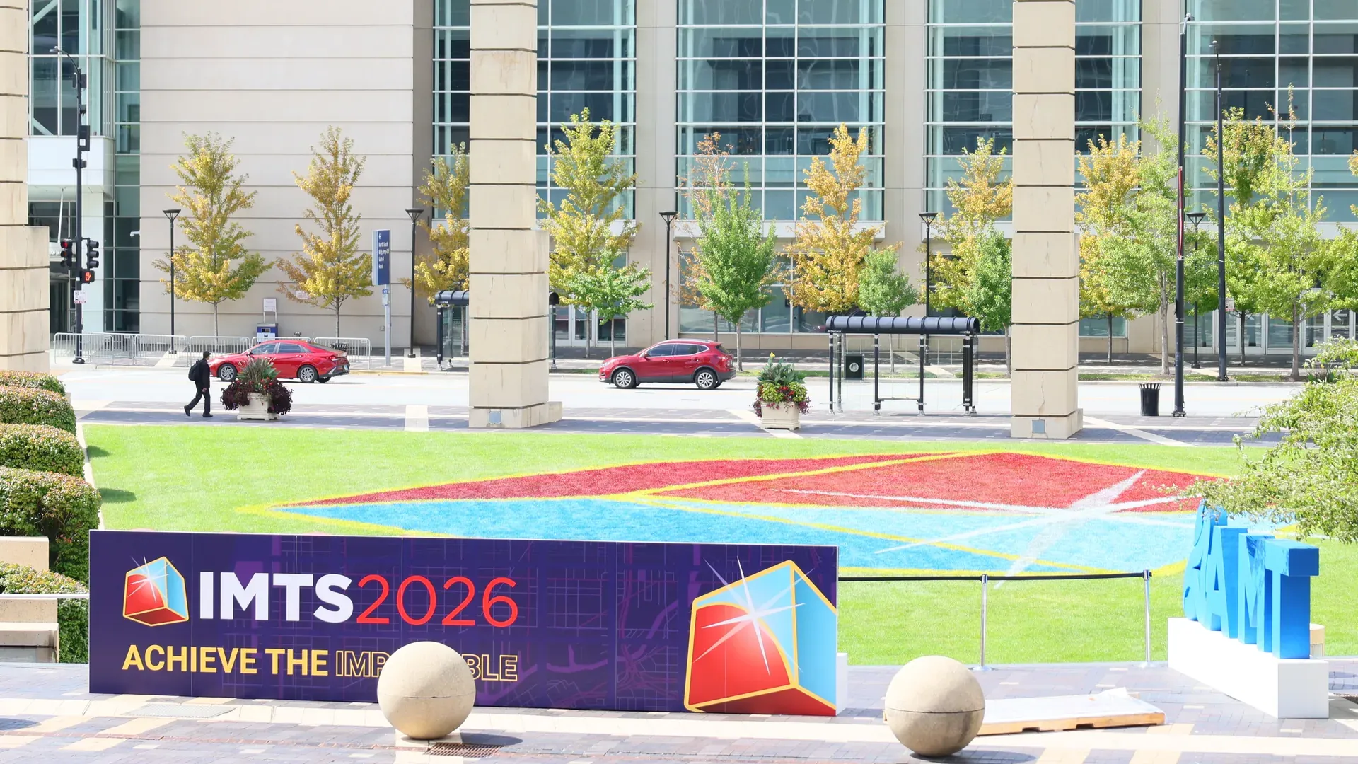 IMTS 2026 'Achieve the Impossible' banner and AMT lettering on the plaza outside McCormick Place, Chicago