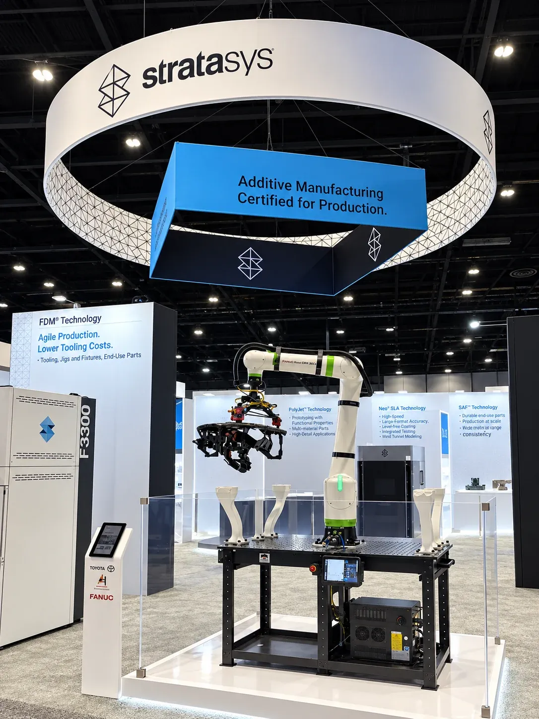 Stratasys booth at IMTS 2026 with an overhead ring sign, an F3300 printer and pillars for FDM, PolyJet, Neo SLA and SAF